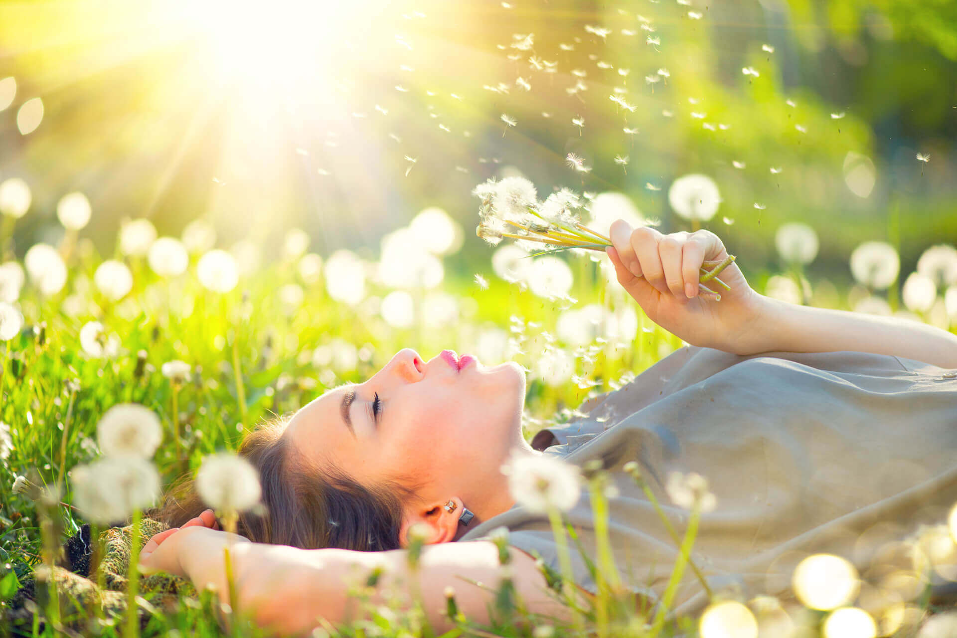 Woman lying in meadow blowing dandelions